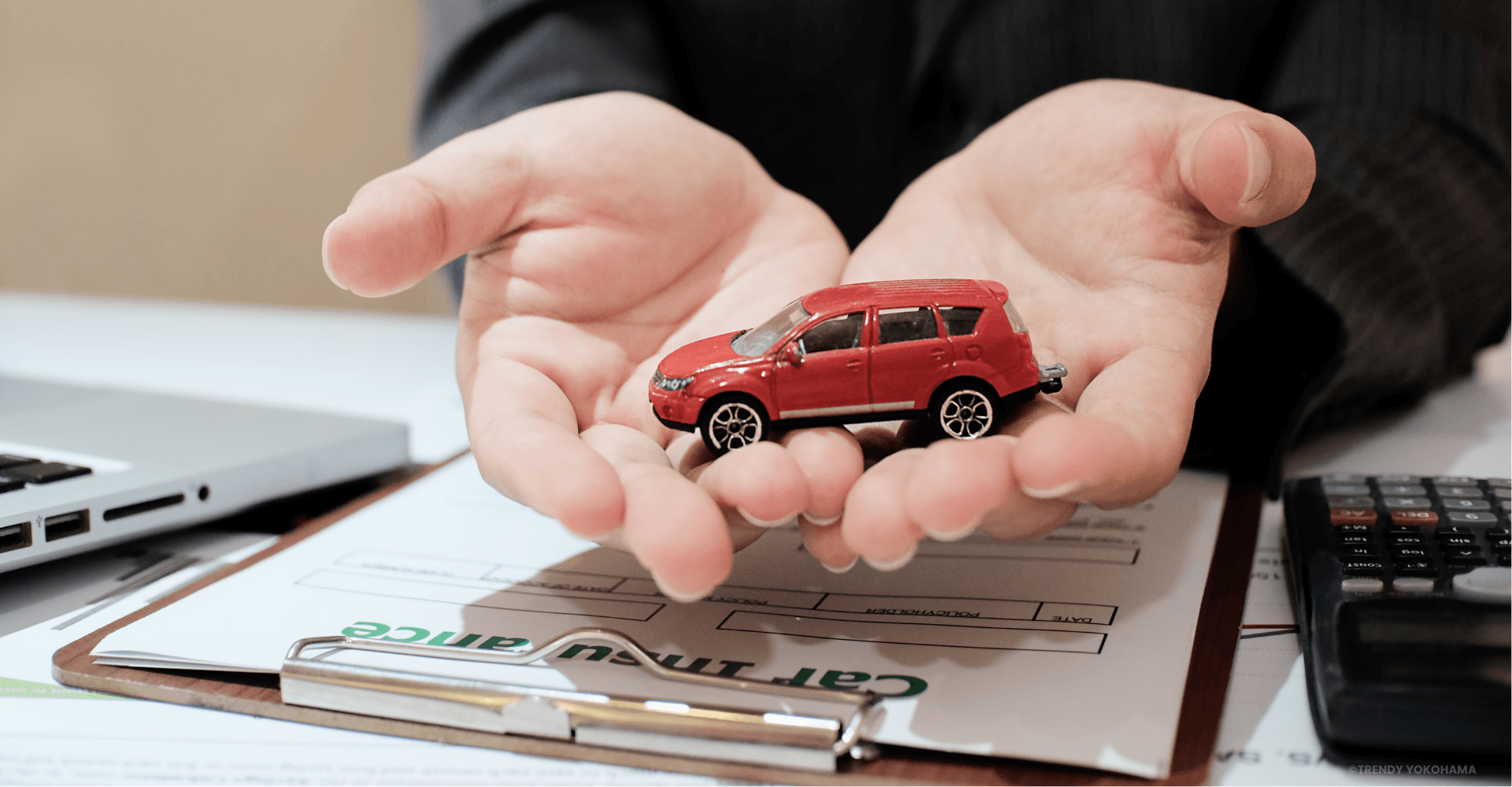 Hands holding miniature car - insurance concept